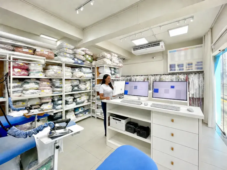 Atendimento da SmartLav com o sistema no computador e as prateleiras de roupa pronta