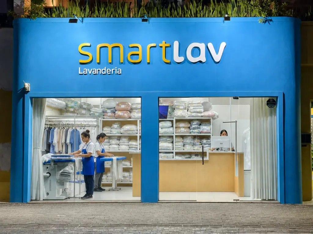 Fachada iluminada da lavanderia SmartLav a noite, no Caminho das Arvores, Salvador